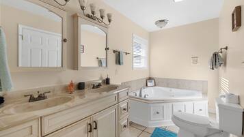 A bathroom with a double sink vanity, a bathtub, and a toilet.