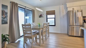 Una cocina moderna con una mesa de comedor, sillas, un refrigerador y un ventanal con cortinas.