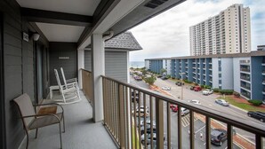 Ein Balkon mit Stühlen und Blick auf einen Parkplatz, im Hintergrund ein hohes Gebäude.