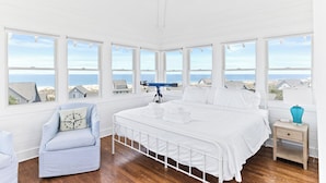 Un dormitorio con una cama grande, un telescopio y vistas al mar.