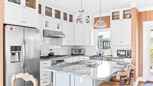 Una cocina moderna con armarios blancos, electrodomésticos de acero inoxidable, encimera de granito y una isla grande con asientos.