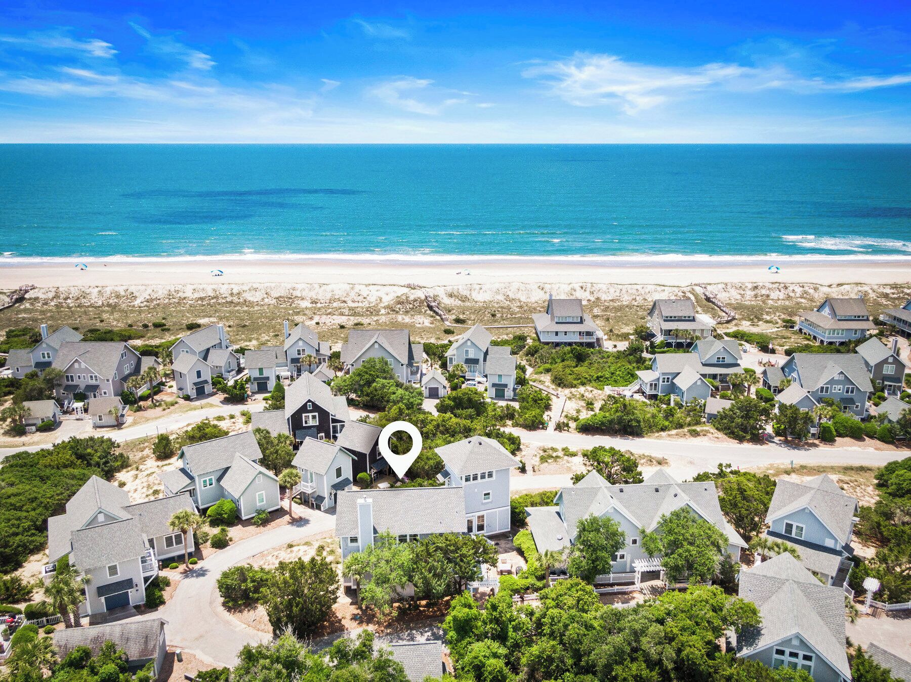 A coastal residential area with houses, a beach, and a clear sky.