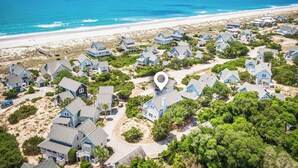 Vista aérea de una zona residencial costera con casas, una playa y el océano.