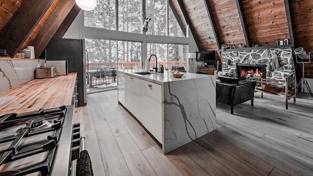 Een moderne keuken met een groot eiland, houten balken en een open haard.