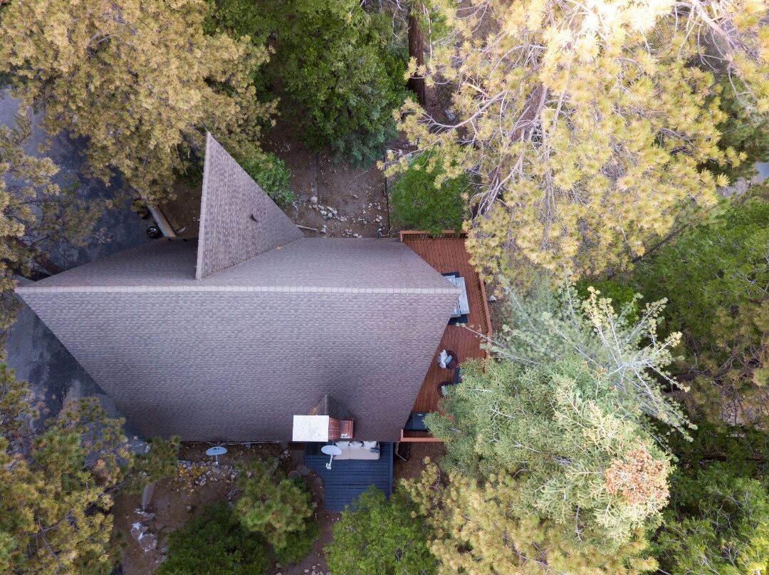 A modern house with a sloped roof, surrounded by trees and a small deck.
