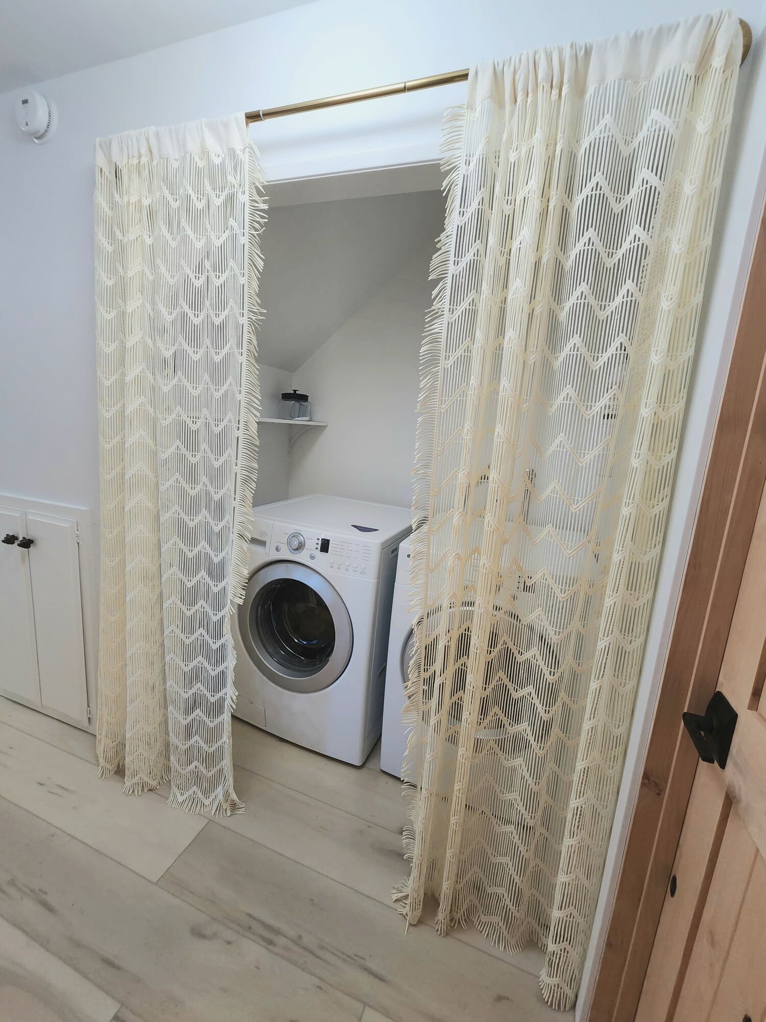 Une petite buanderie équipée d’un lave-linge, d’un étendoir et d’une étagère avec des boîtes de rangement.