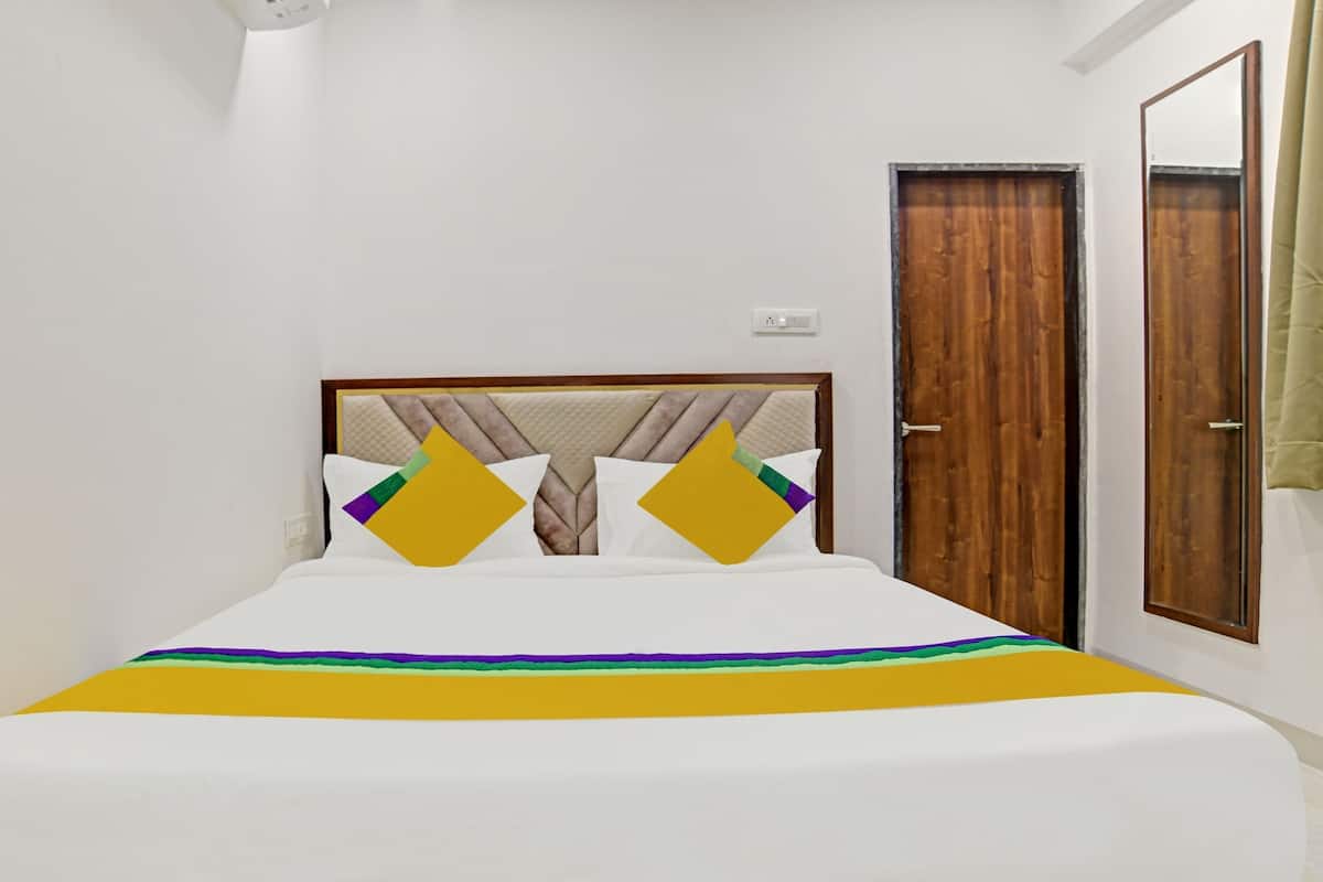 Una habitación de hotel con una cama, una puerta de madera y un espejo.