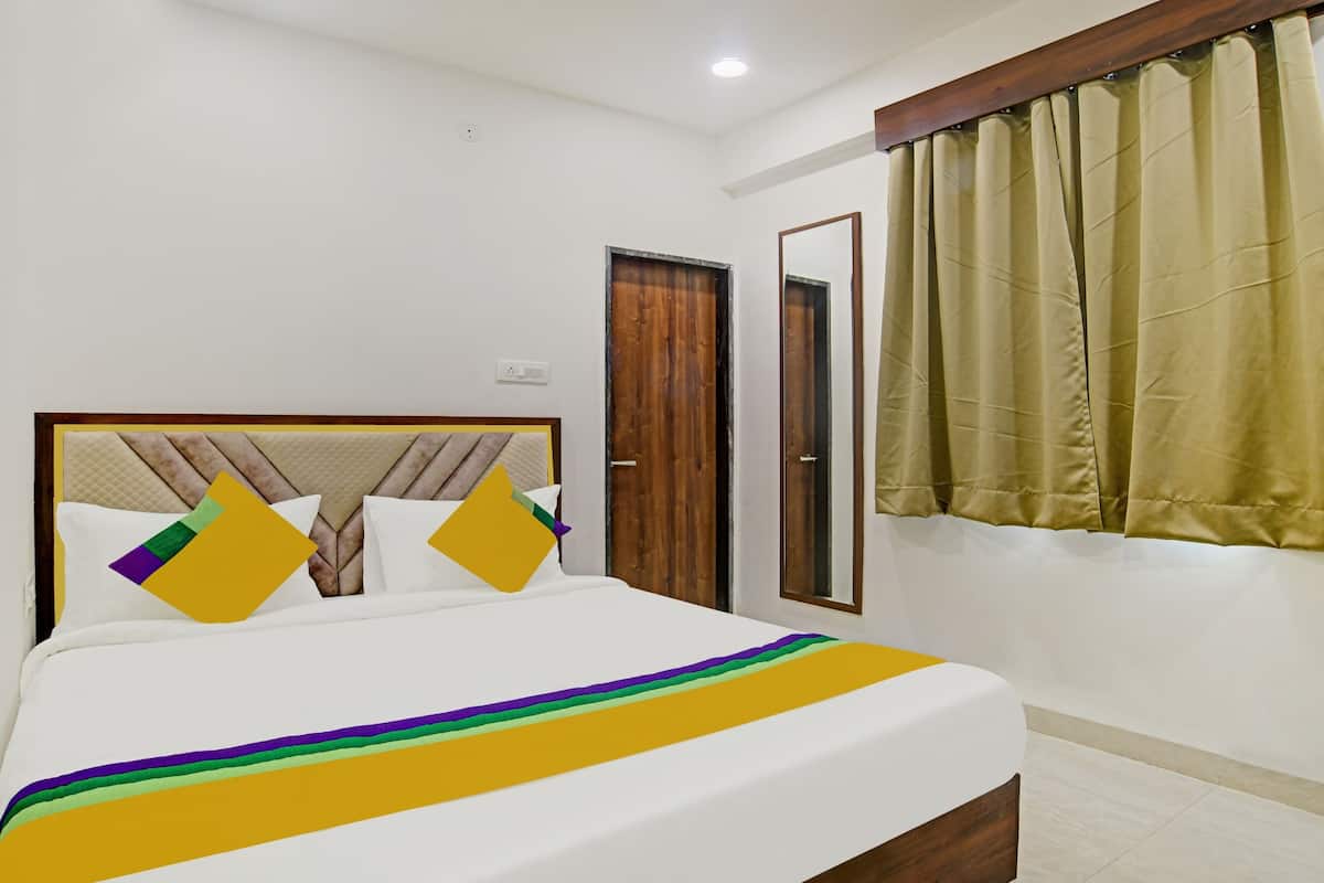 Una cama bien hecha con cabecera de madera, un espejo y una ventana con cortinas.