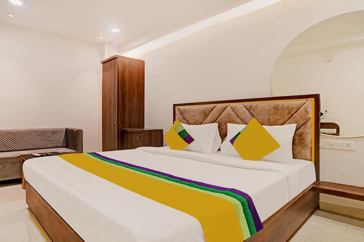 Una habitación de hotel con cama, sofá, armario y mesita de noche.