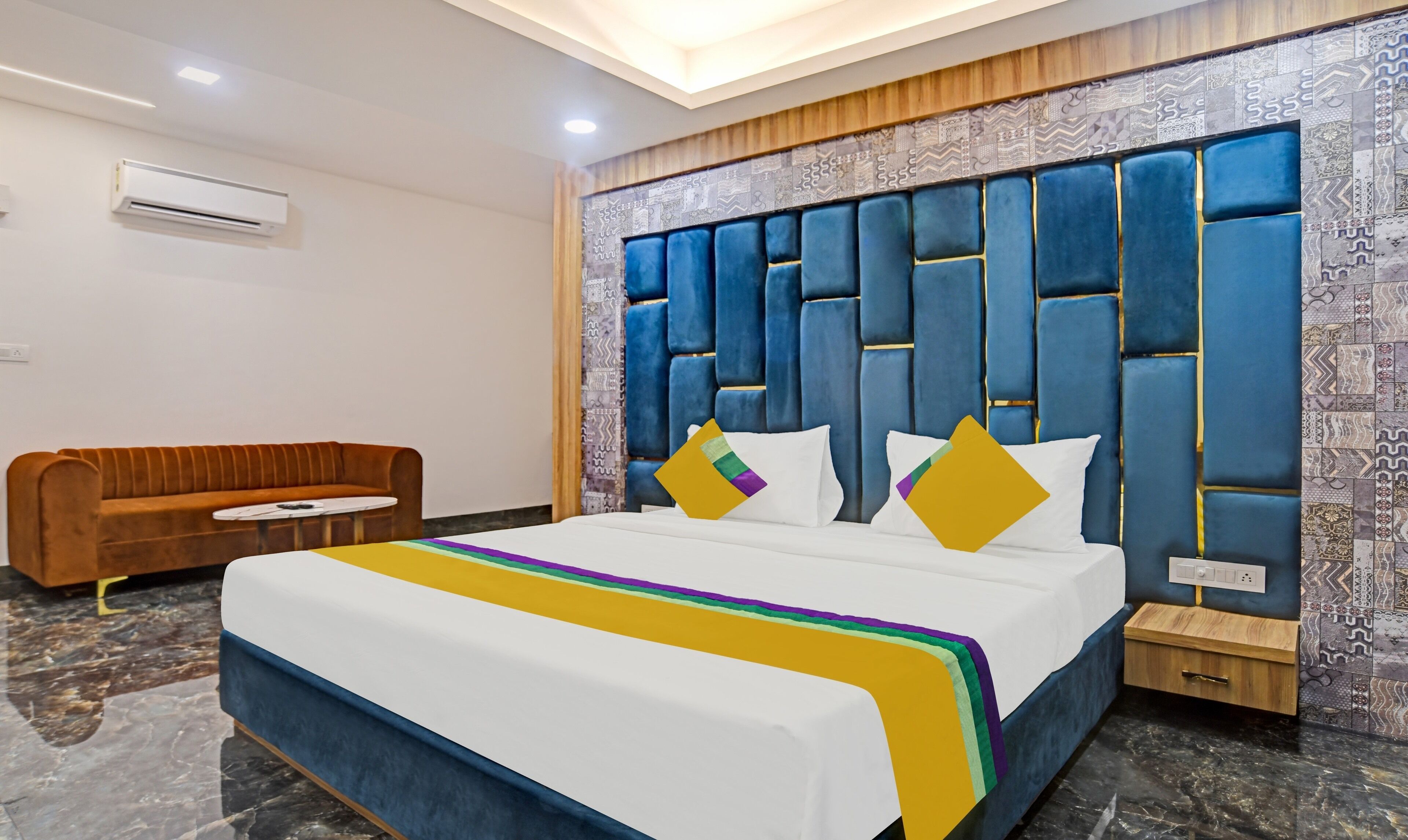 Una camera d'albergo moderna con un letto grande, un divano e una parete decorata.