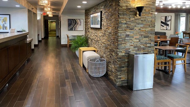 A modern hotel lobby with a stone wall, wooden flooring, and a reception desk. - The Addison Hotel, SureStay Collection by Best Western (Addison)