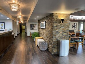 Un moderno vestíbulo de hotel con pared de piedra, suelo de madera y un mostrador de recepción.