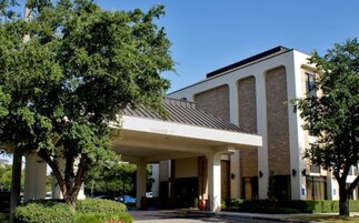 Un hotel con un acceso cubierto, ventanas amplias y fachada de ladrillo.