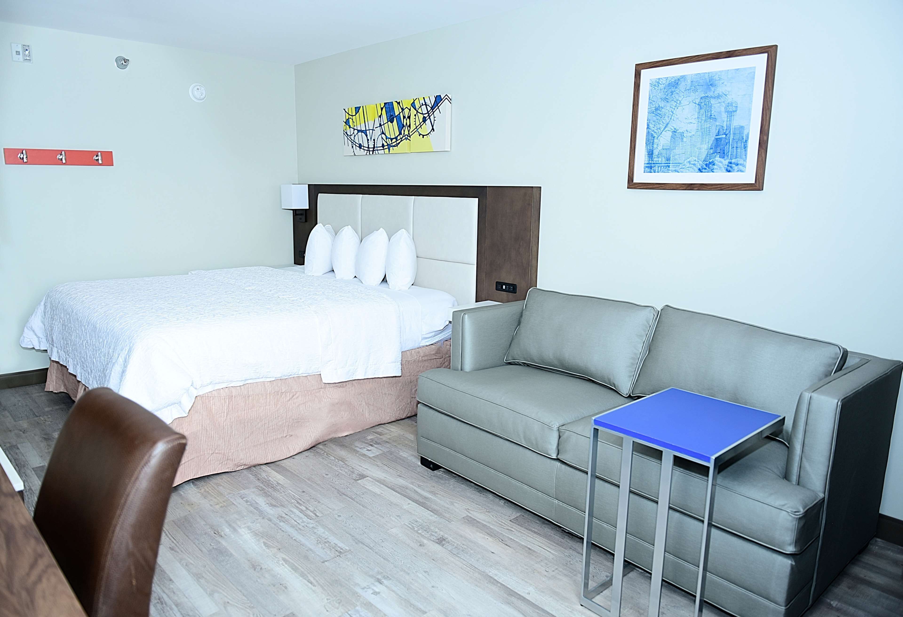 Ein Hotelzimmer mit einem Bett, einem grauen Sofa, einem kleinen Tisch und einem Sessel.