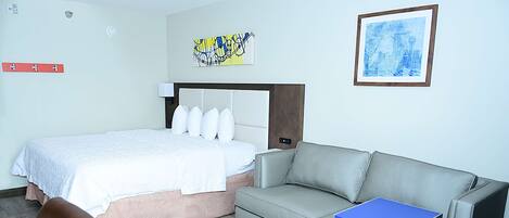 Ein Hotelzimmer mit einem Bett, einem grauen Sofa, einem kleinen Tisch und einem Sessel.