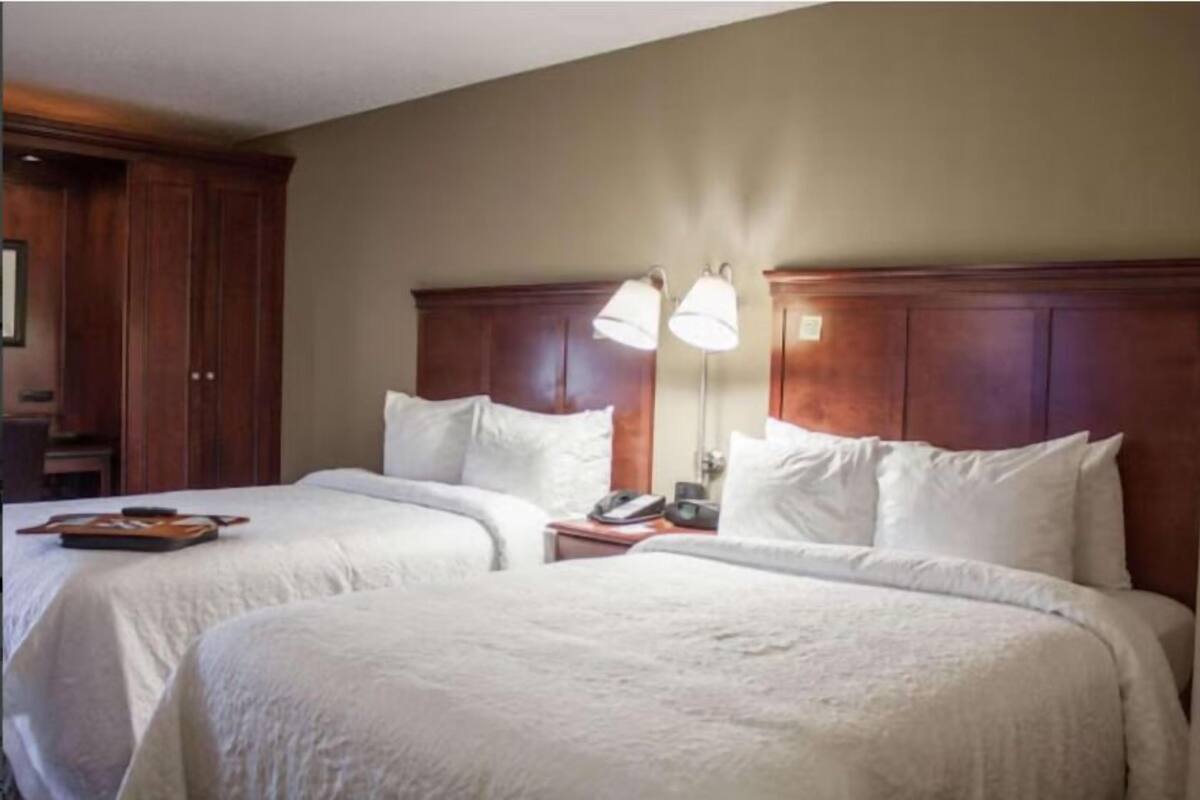 Une chambre d’hôtel avec deux lits, des têtes de lit en bois et des lampes de chevet.