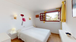 A bedroom with a bed, bedside tables, a window with curtains, and wall decorations. - Villa Raphael 8 people with pool  (Alcúdia)