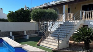 A residential property with a swimming pool, a staircase leading to a balcony, and a well-maintained lawn. - Villa Raphael 8 people with pool  (Alcúdia)