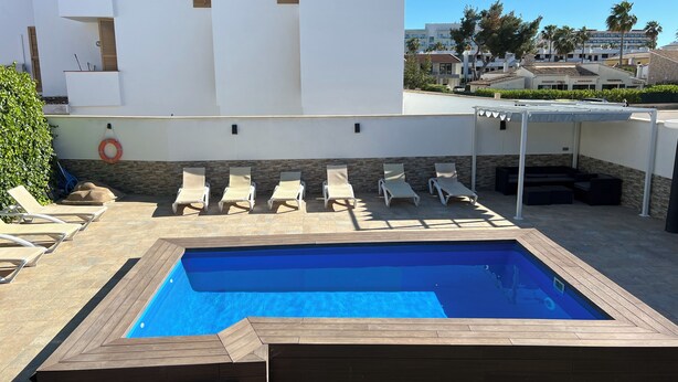 A rooftop pool area with lounge chairs and a wooden deck surrounding a rectangular pool. - Villa Raphael 8 people with pool  (Alcúdia)