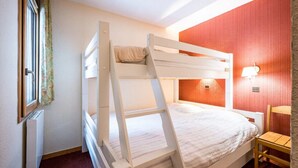 A bunk bed room with a window, radiator, and a lamp on the wall. - Apartment, les Avanchers Valmorel, sleeps 6. (Les Avanchers-Valmorel)
