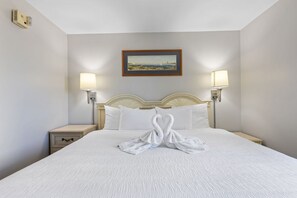 A hotel room with a large bed, two bedside lamps, a framed picture on the wall, and a towel art on the bed. - Oceanfront Condo in Atlantica Resort (Myrtle Beach)