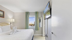Hotelkamer met een bed, een raam met gordijnen, een wandtelevisie en uitzicht op de stadszicht.