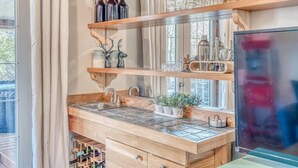 Une cuisine avec des étagères en bois, un évier et divers ustensiles de cuisine.