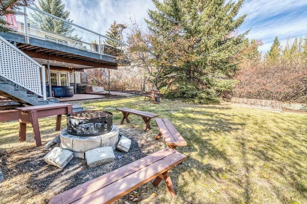Un jardin avec un foyer, des tables de pique-nique et un espace extérieur couvert.
