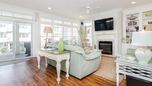 A spacious living room with a light green sofa, a white coffee table, and a fireplace. - 3 Bedroom Lower Duplex w Ocean Views and Game Room (Wrightsville Beach)