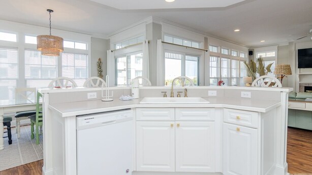 A spacious kitchen with white cabinetry, a large island, and a dining area with green chairs. - 3 Bedroom Lower Duplex w Ocean Views and Game Room (Wrightsville Beach)
