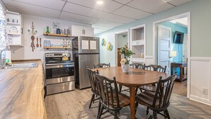 Eine moderne Küche mit Edelstahlgeräten, einem Holzespeisetisch und Blick in das angrenzende Wohnzimmer.
