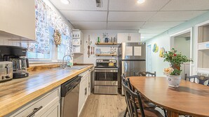 Eine moderne Küche mit Edelstahlgeräten, Holz Arbeitsplatten und einem Essbereich mit Tisch und Stühlen.