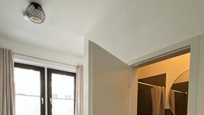 Ein Schlafzimmer mit einem Bett, einem Fenster und einer Tür zu einem Badezimmer.
