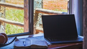 A laptop on a desk by a window with a view of the beach. - Beautiful House, Wave/Surf Steps. Point of Wolves (pichilemu)
