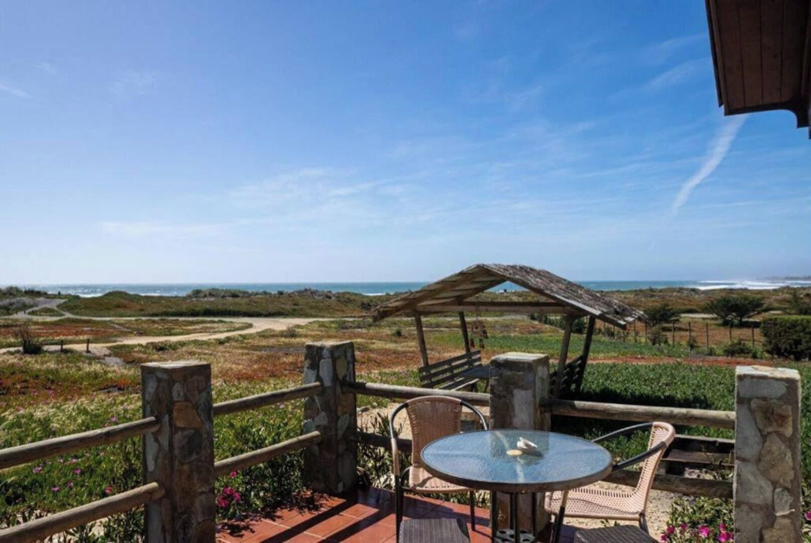 Une terrasse avec une table et des chaises donnant sur un paysage côtier.
