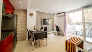 A modern dining area with a TV, a clock, and a table set for two.
