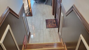 A wooden staircase with a doormat at the top.