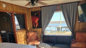 A room with a bed, a sofa, a wooden table, and a window with curtains.