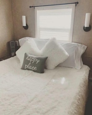 Relax in a serene bedroom with a plush bed, adorned with pillows and a window for natural light.