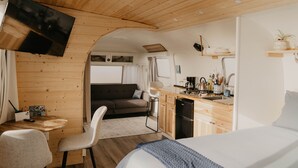 Een compact RV-interieur met een kitchenette, een eethoek en een slaapgedeelte.