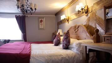 A hotel room with a large bed, a wooden headboard, a nightstand, and a chandelier.