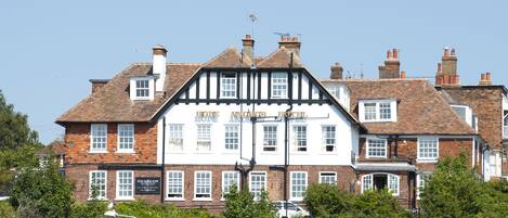 Un edificio de estilo Tudor tradicional con numerosas ventanas y un letrero que indica que es un hotel.