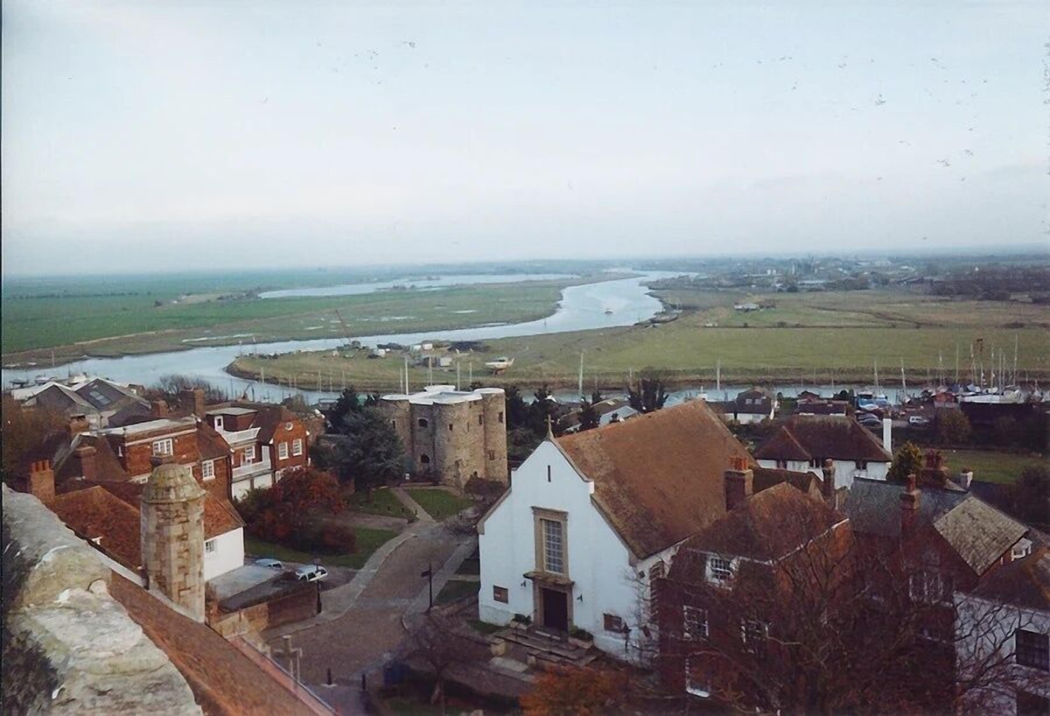 Eine Küstenstadt mit einer markanten weißen Kirche, einer Burg und einem Fluss.