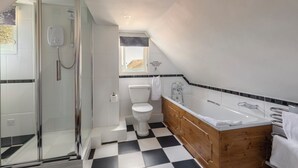 Un baño moderno con cabina de ducha de vidrio, inodoro blanco, tocador de madera con bañera y piso a cuadros.