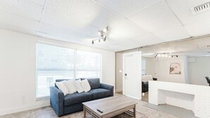 A modern living room with a grey sofa, a wooden coffee table, and a large window with a view. - PRAIA Hotel Hollywood (Hollywood)
