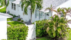 A white two-story house with a tiled roof, surrounded by lush greenery including palm trees and bushes. - PRAIA Hotel Hollywood (Hollywood)