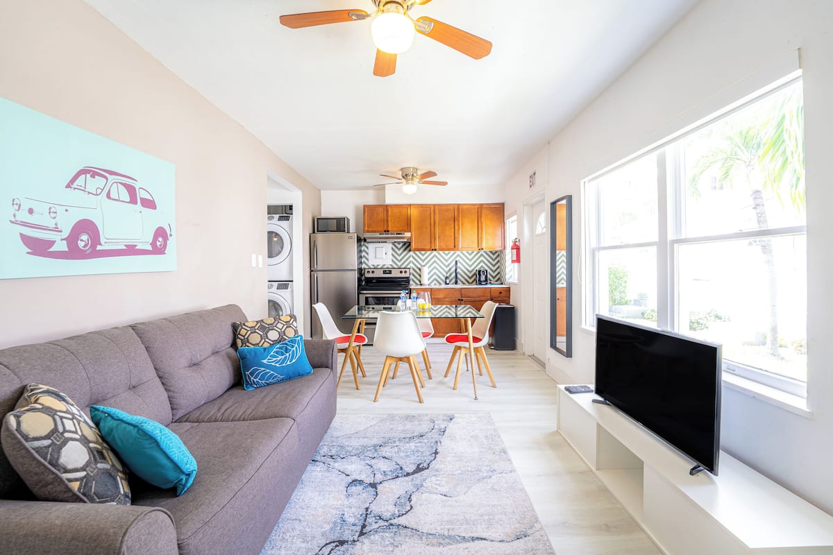 Un salon moderne comprenant un canapé, un téléviseur et un coin repas avec des chaises et une table.