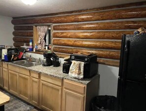 Eine Küche mit Holzbalkenwänden, einer Arbeitsplatte aus Granit und einem schwarzen Kühlschrank.