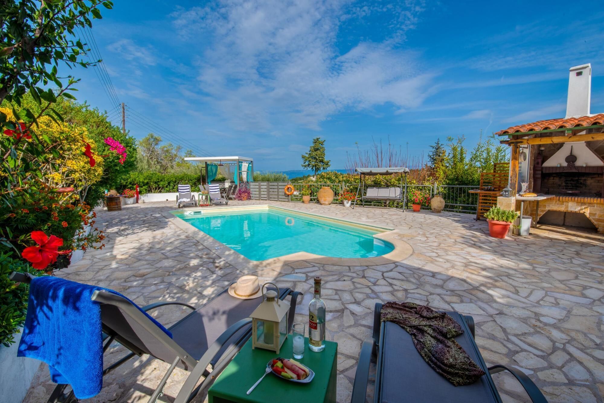 A pool area with lounge chairs, a barbecue, and a gazebo.