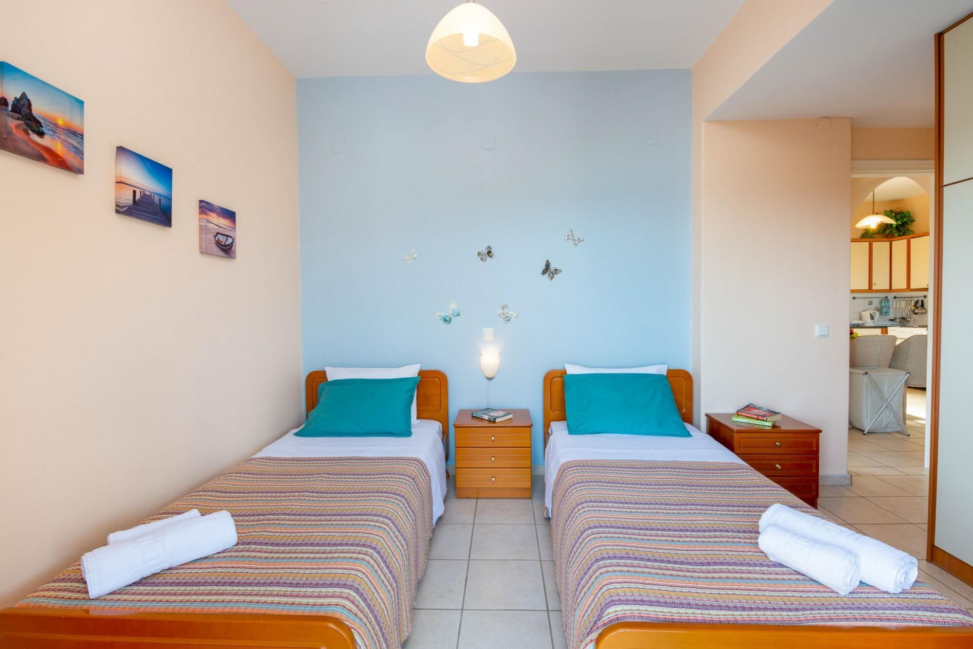 A twin room with two beds, a nightstand, a wall-mounted lamp, and butterfly decals.